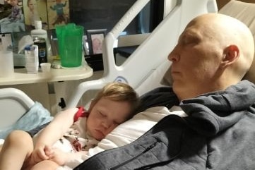 a man and his daughter sleeping in a hospital bed 