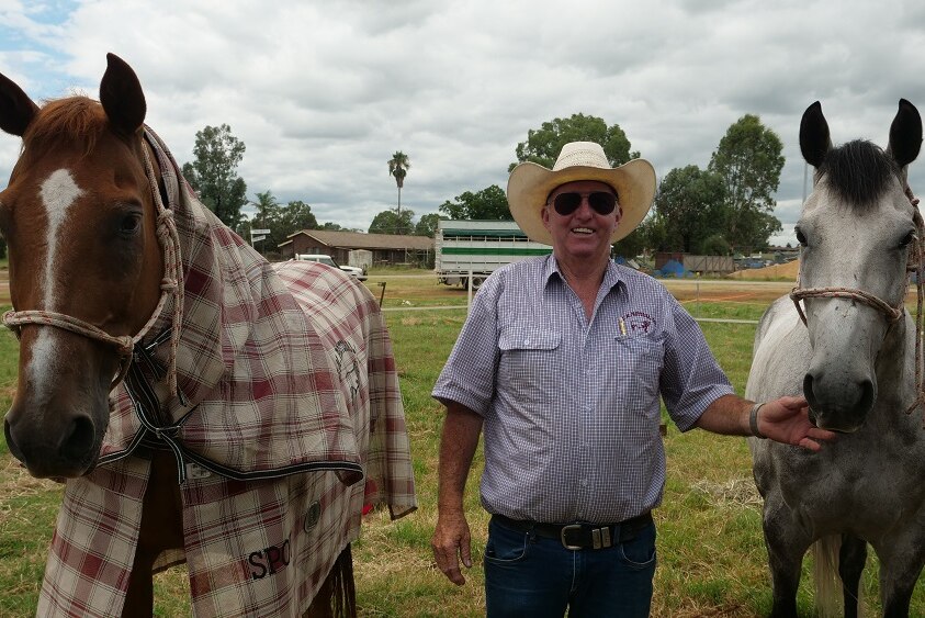 Criag McNabb stands between his horses in their paddock.
