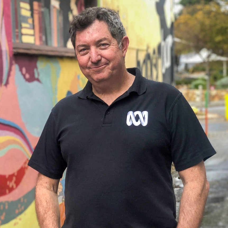 Peter Barr, standing with his hands in his pockets, in front of a brightly painted street mural.