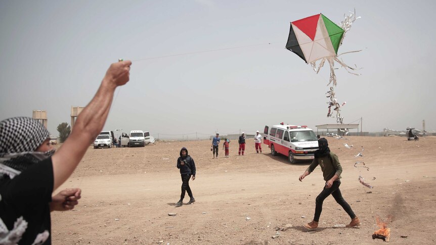 Palestinian protesters fly a kite with a burning rag dangling from its tail during a protest.