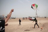 Palestinian protesters fly a kite with a burning rag dangling from its tail during a protest.