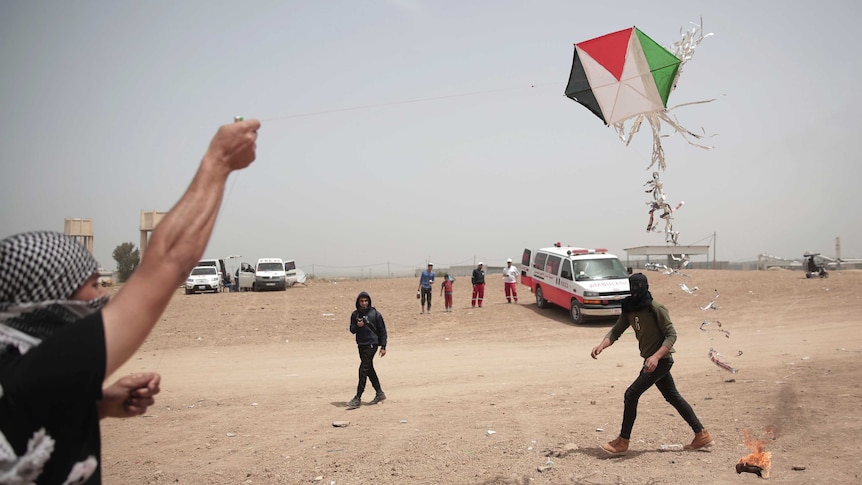 Palestinian protesters fly a kite with a burning rag dangling from its tail during a protest.