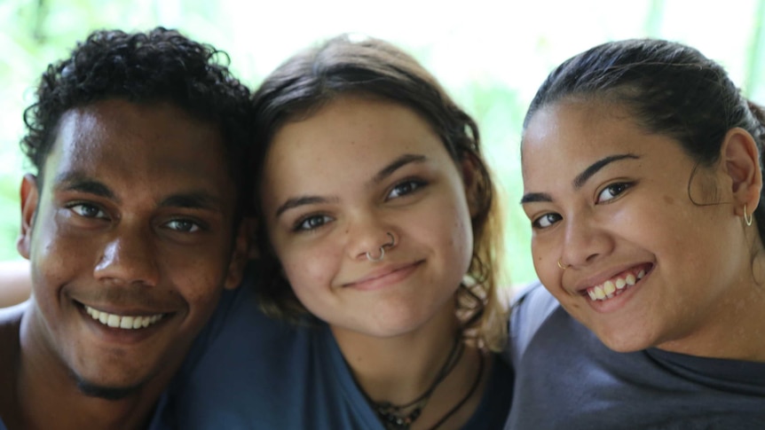 Three young people smiling and embracing