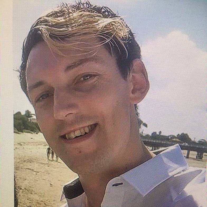 A man with a mix of blonde and dark hair smiles at the camera.