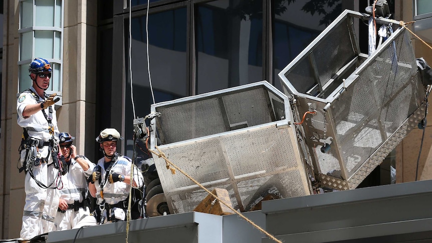 Emergency services stand beside a wrecked metal window cleaning cage
