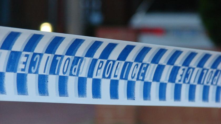 A close-up shot shows police tape in front of a nondescript scene, with an unidentifiable car parked in a garage.