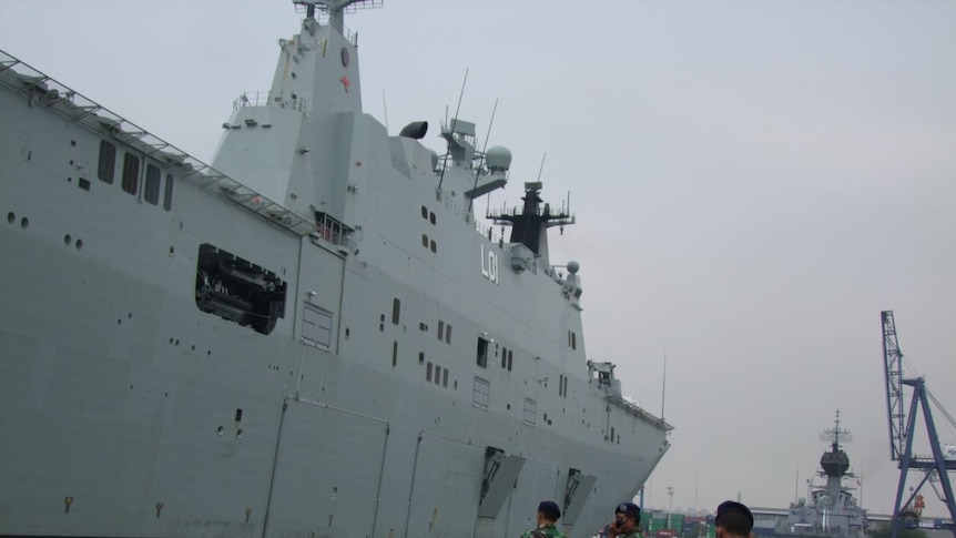 Indonesia military men standing on the dock next to a HMAS ship.