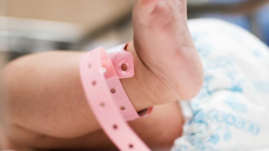 A baby foot with a pink tag around the ankle.