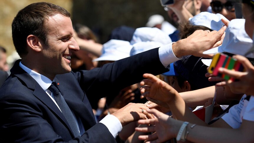 Emmanuel Macron smiles as he greets supporters.
