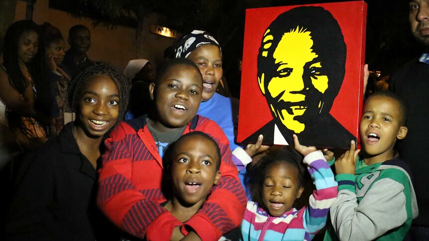 South Africans hold a portrait of former South African president Nelson Mandela as they pay tribute following his death.