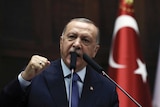 Turkish President Recep Tayyip Erdogan is speaking from podium in parliament the Turkish flag is behind him