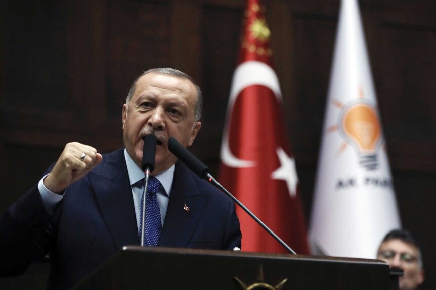 Turkish President Recep Tayyip Erdogan is speaking from podium in parliament the Turkish flag is behind him