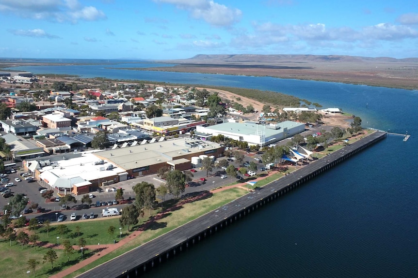 An aerial shot of Port Augusta, with blue waters and distant horizon, a few clouds in the sky.