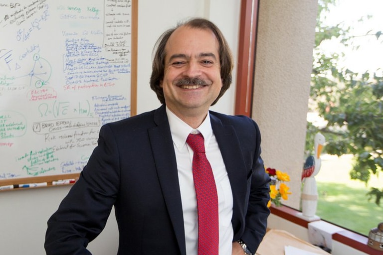 A man in a suit in front of a whiteboard in the classroom