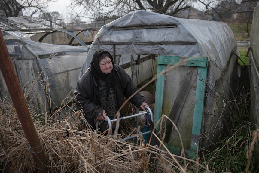 Olga Lehan walks in a yard of her house.