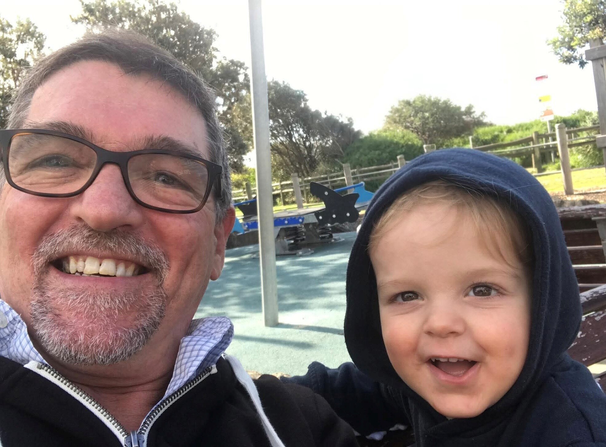 চশমা এবং সাদা দাড়ি সহ বয়স্ক ব্যক্তি একটি হুডি পরা একটি বাচ্চা সঙ্গে একটি সেলফি তুলেছে