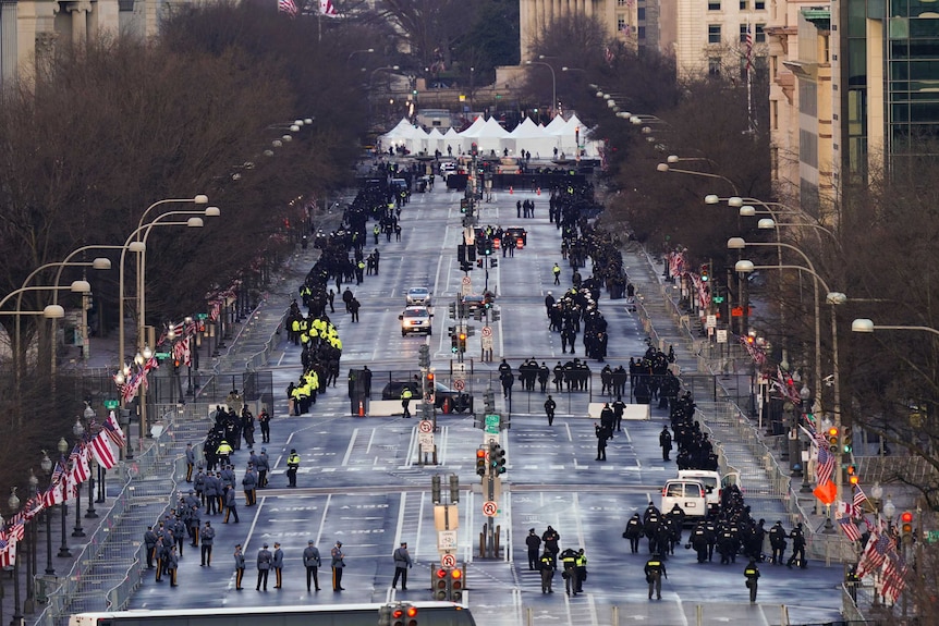 An aerial shot of a wide avenue with a large number of uniformed people.