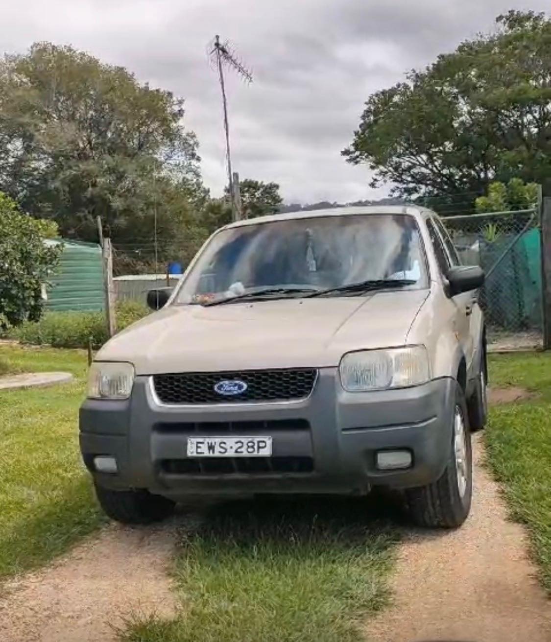 A Ford SUV in a pale metallic colour parked on a country property.