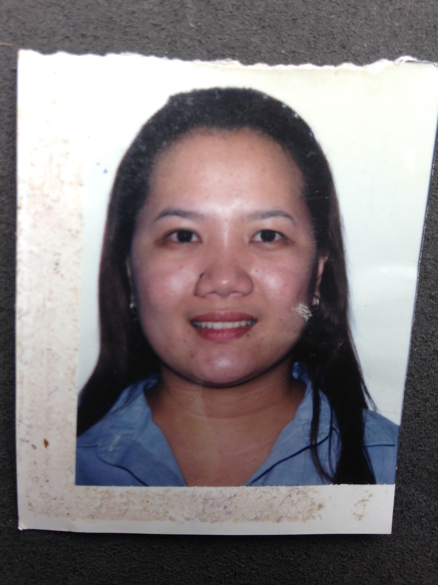 A passport photo of a woman with long black hair wearing a blue shirt.