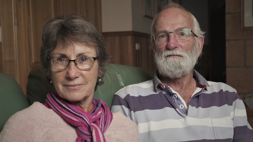 A woman and man sit next to each other on a sofa.