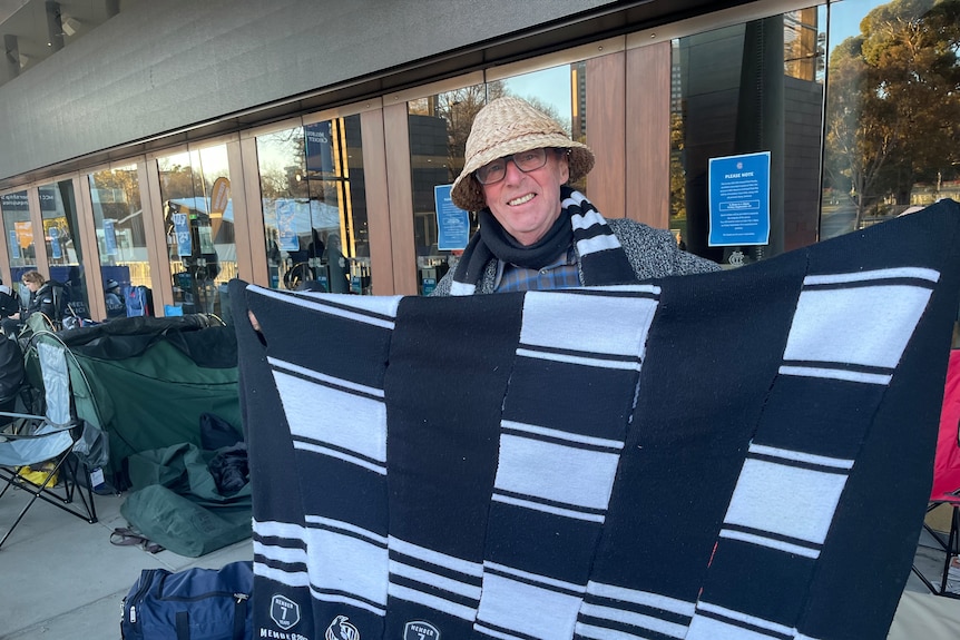 Peter Whitfield holds up fabric in Collingwood colours.