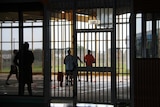 Unidentified figures behind bars at Darwin's Don Dale youth detention centre. 