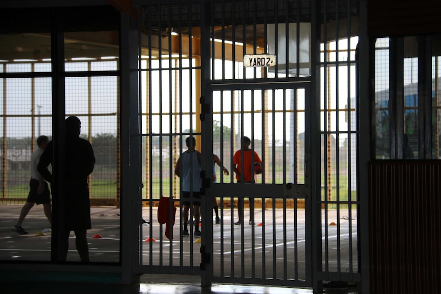 Unidentified figures behind bars at Darwin's Don Dale youth detention centre. 