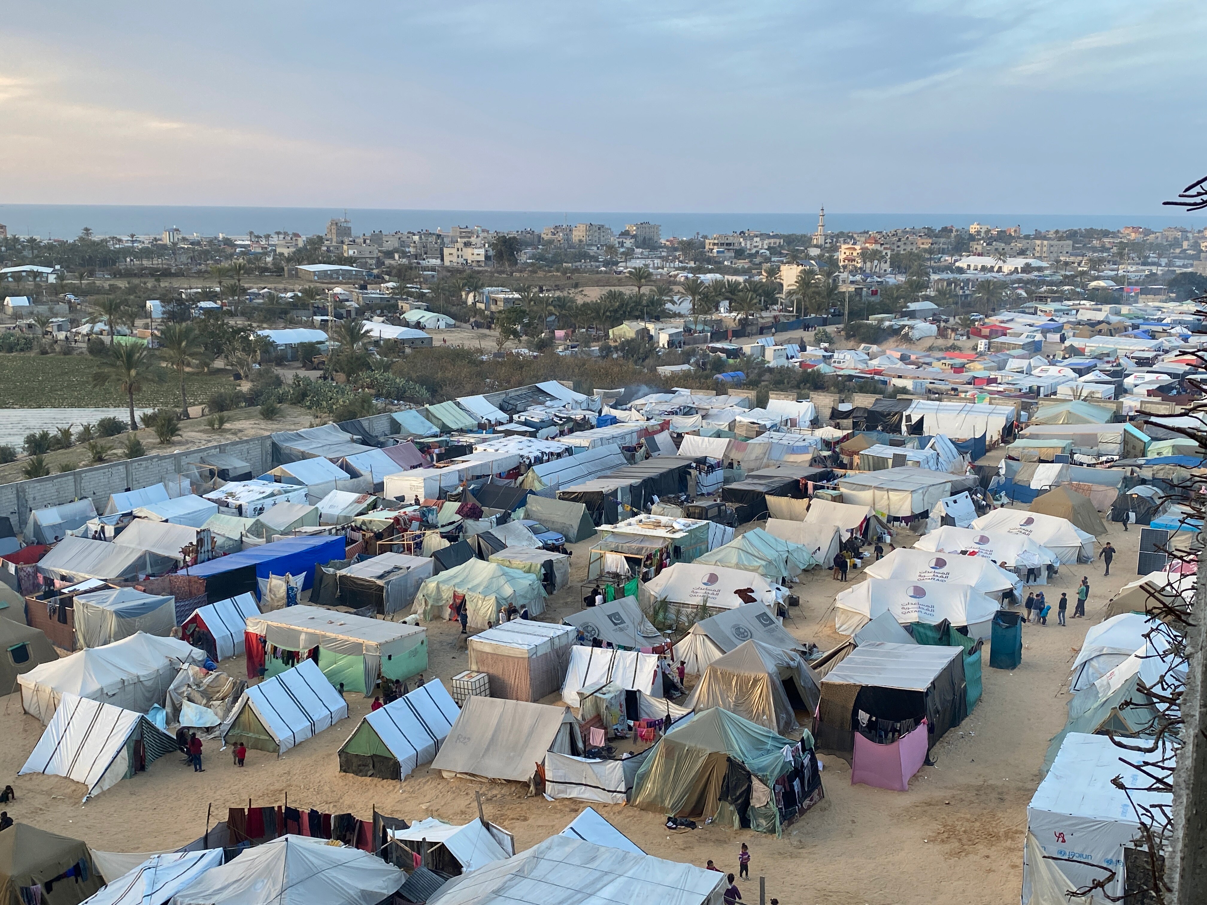 Dozens of tents pictured in a refugee camp. The sea is in the distance.