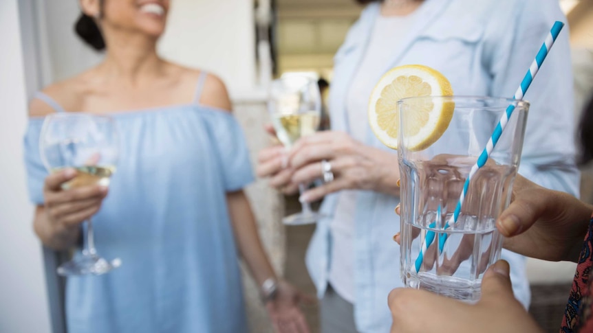 Women drinking lemon water while others drink white wine.