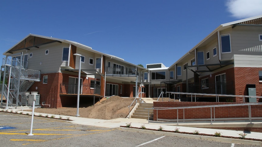 A new building with brown brick on the ground floor and taupe cladding on the second floor.