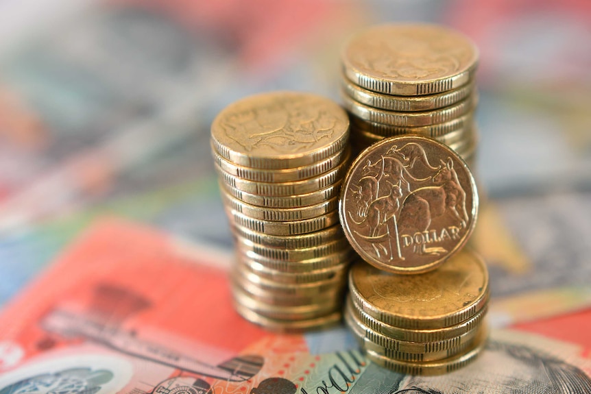 A pile of Australian dollar coins on top of several bank notes