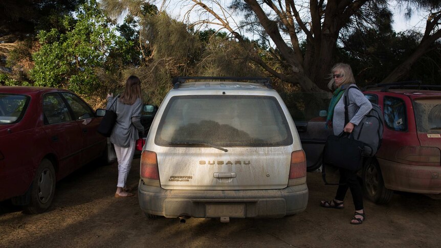 Teachers get into a car so dusty the lettering of the number plate is barely visible.