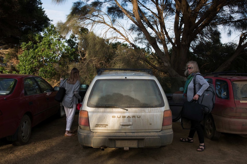 Teachers get into a car so dusty the lettering of the number plate is barely visible.