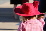 Two girls in broad brim hats and school uniforms.