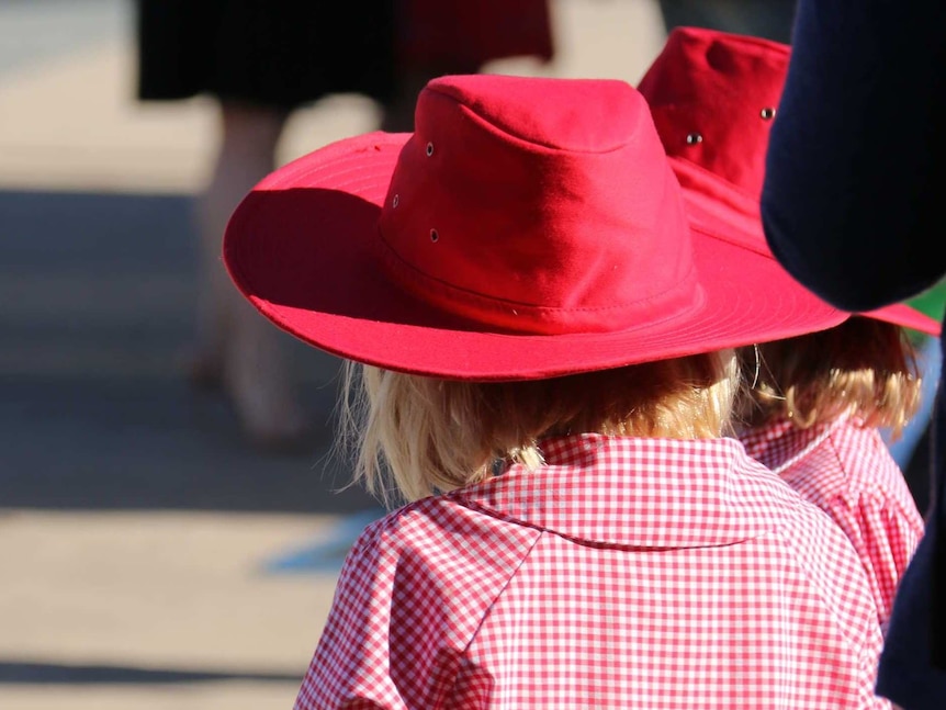 Two girls in broad brim hats and school uniforms.