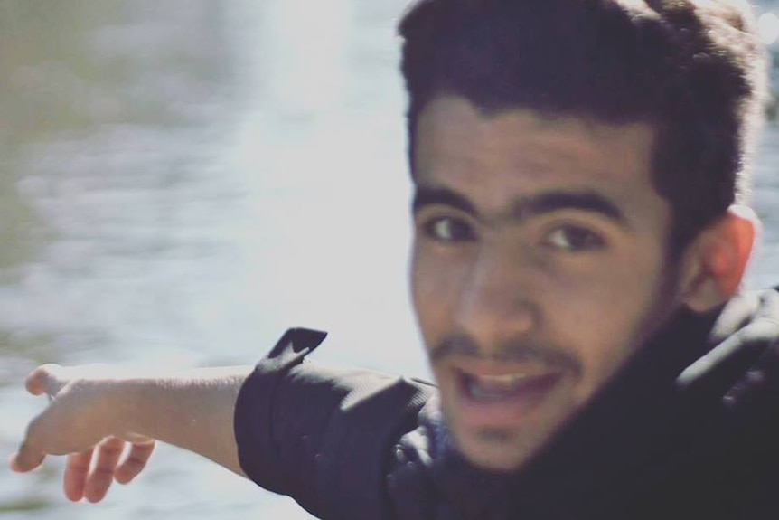 A smiling young in front of water.