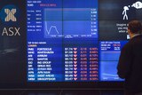 A man stops to look at the electronic share board at the Australian Stock Exchange in Sydney