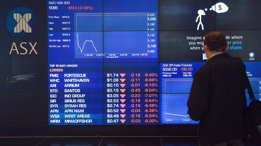 A man stops to look at the electronic share board at the Australian Stock Exchange in Sydney