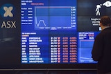 A man stops to look at the electronic share board at the Australian Stock Exchange in Sydney on August 24, 2015.