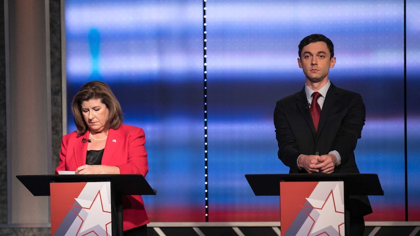 Republican Karen Handel and Democrat Jon Ossoff stand side by side at two podiums for a debate