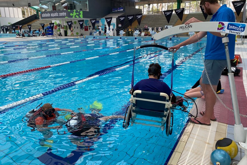 A person is lowered into the water as part of immersion therapy.
