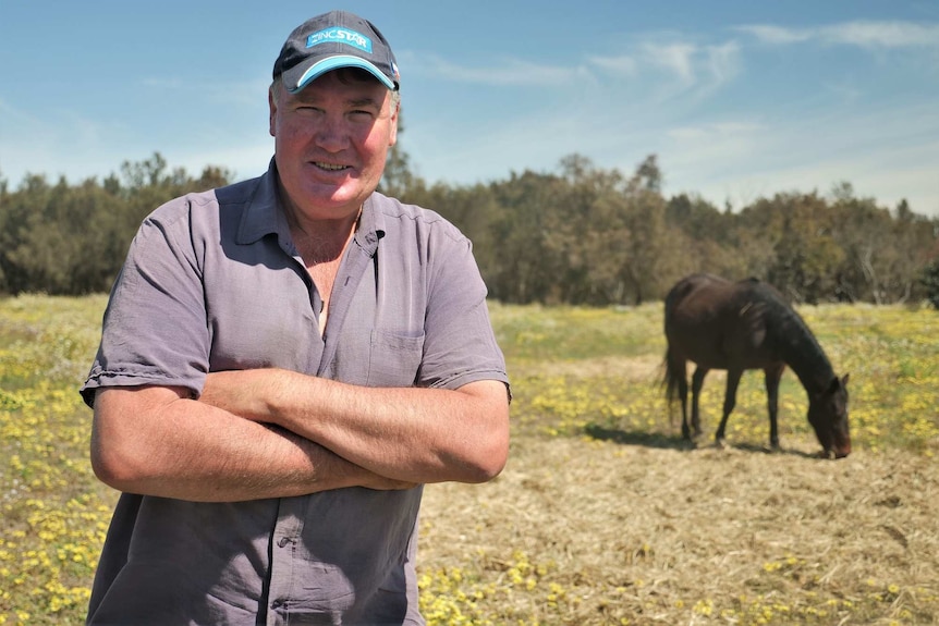 Kevin Spurr standing in a paddock with a horse in the background