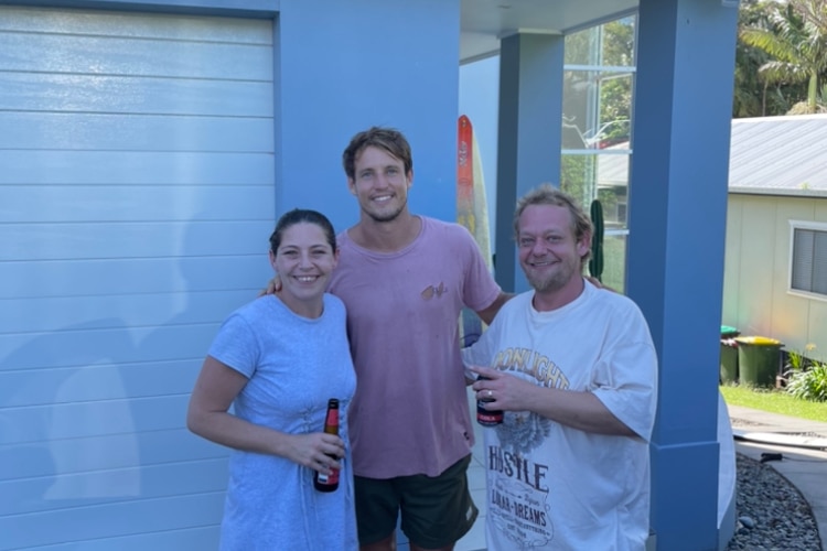 Three people pose for a photo holding beverages.