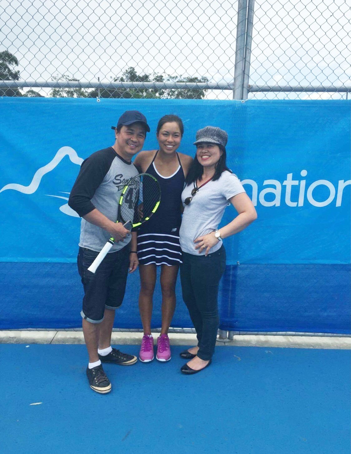 Lizette Cabrera with her mother and father on a tennis court.
