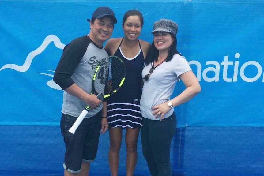 Lizette Cabrera with her mum and dad at a tennis court.