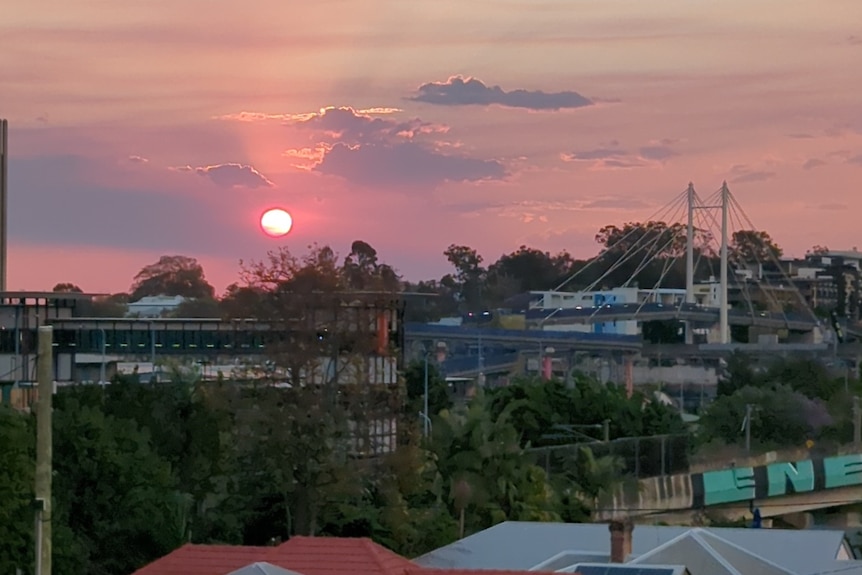 A pink sun sets over Brisbane.