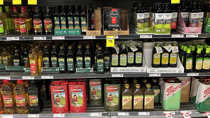 Olive oil bottles lined up on supermarket shelves.