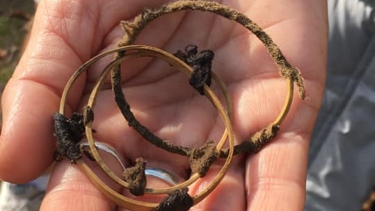 An outstretched hand holding three dirty hair ties.