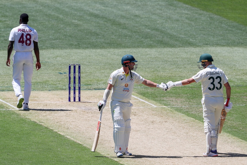 Travis head and Marnus Labuschagne fist bump in the middle of the pitch
