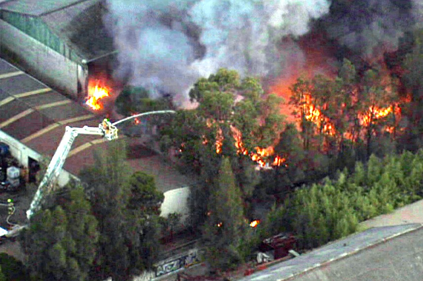 A firefighter in a cherry picker sprays a large fire with a hose